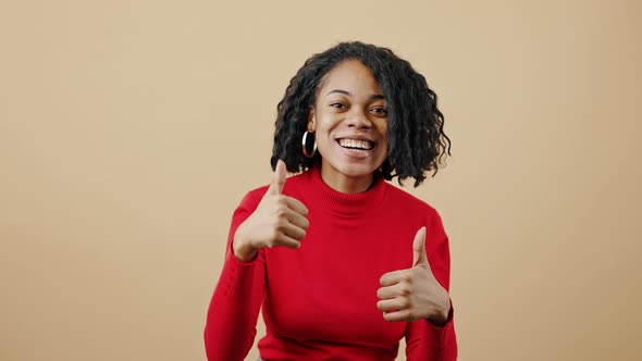 Young Happy African American Woman Looking at Camera with Excitement and Showing Thumbs Up with Both