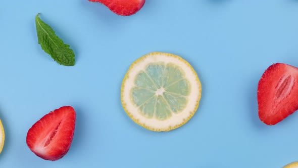 A Rotating Background of Blueberries Strawberries Lemon Slices and Mint Leaves on a Blue Background