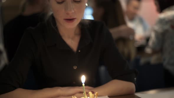 Blonde Woman Blowing Out a Birthday Cake in the Restaurant