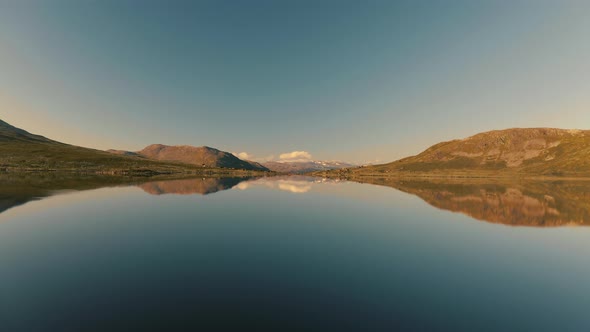 Magnificent Mountain Range Perfectly Reflected On The Tranquil Lake Water In Norway Under The Clear