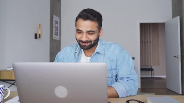 Young Happy Attractive Indian Man Having Video Call at Home Office Using Pc