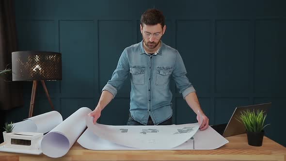 Close Up Shot of Young Man Hands Engineer Opening the Paper and Checking the Construction Drawings