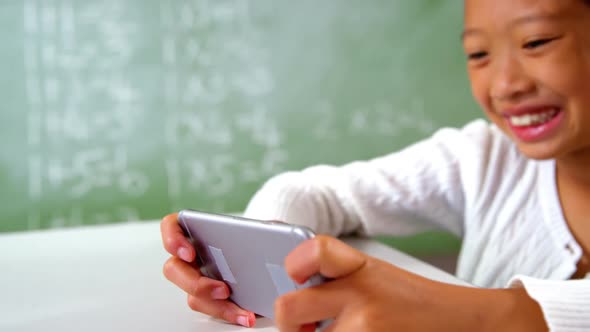 Schoolgirl using mobile phone in classroom at school