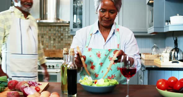 Senior couple preparing salad in kitchen