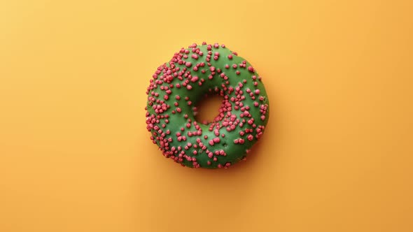 Top View Appetizing Fresh Tasty Doughnut Covered By Green Icing and Pastry Topping Rotating