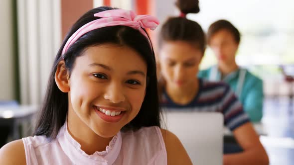 Portrait of smiling schoolgirl studying in classroom