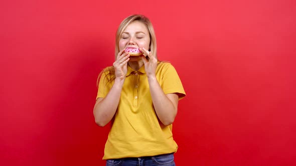 Cute, Fat Girl in a Yellow T-shirt Holding a Donut in Her Hand, She Can't Help Herself and Starts