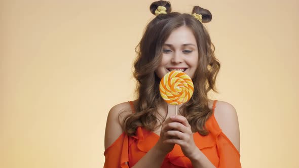 Cute girl with caramel candy on colored studio background