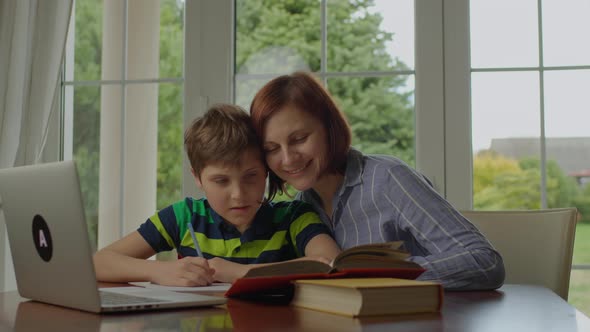 Young 30s Mother Making Online Homework with School Kid at Home