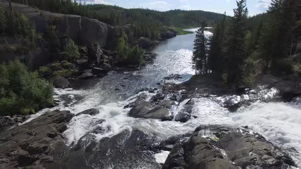 Overflying a picturesque rushing waterfall in rugged backcountry.