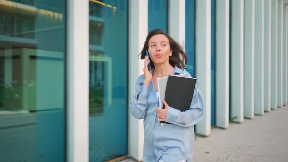 Busy Young Female Office Worker Running in the Street While Speaking on Smartphone