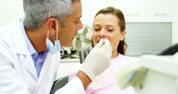 Dentist examining a female patient with tools