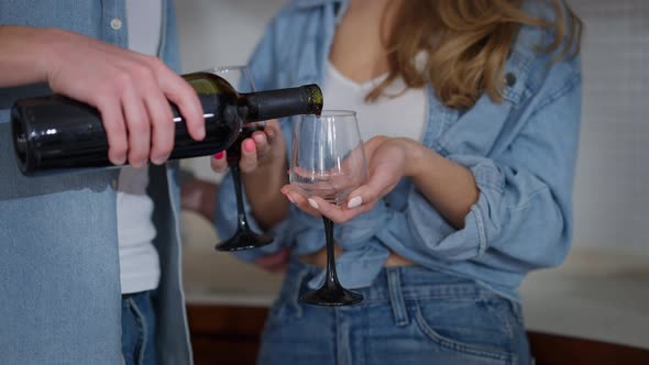 Closeup Male Hand Pouring Red Wine in Two Glasses in Female Hands