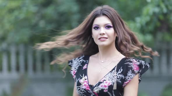 Childish Girl in Floral Dress Laughing and Twirling Around