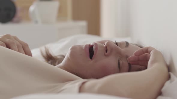 Portrait of Adult Beautiful Woman Lying on the Bed Yawning