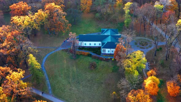 Flight in the evening over trees, park, building. The trees are covered with red, yellow.