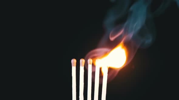 Chain Reaction of Five Matches Lit and Flame on a Black Background