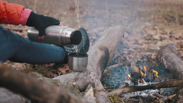 Traveler Girl Pouring Tea From Thermos Cup During Hike. Woman Pouring a Hot Drink in Mug From