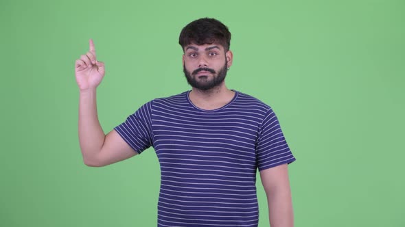 Happy Young Overweight Bearded Indian Man Pointing Up