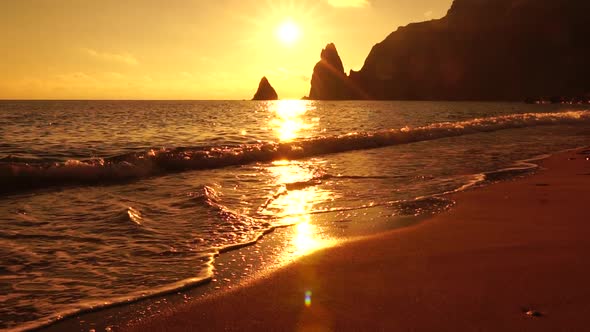 A Red Burning Sunset Over the Sea with Rocky Volcanic Cliff