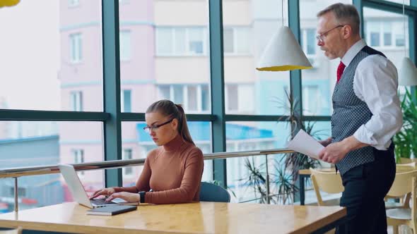 Young woman working on a computer near the window.