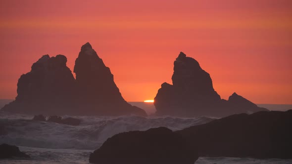 Two pillars cut through the red haze as the sun fades on an Oregon beach.