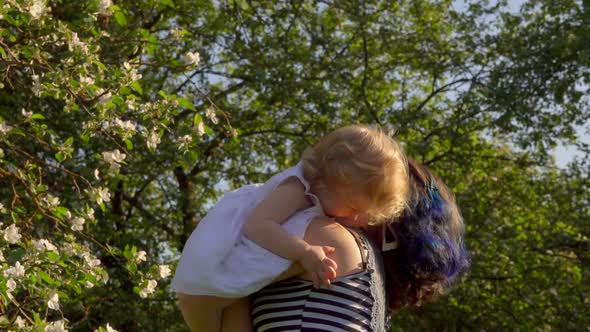 Mom Is Throwing Up and Kissing a Little Adorable Daughter in White Dress