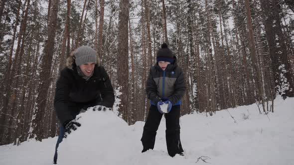 Caucasian Dad and Son Having Fun Building Snowman