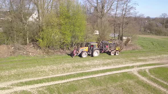 Aerial shot tractor driving in the middle of the day on a rural farm field.