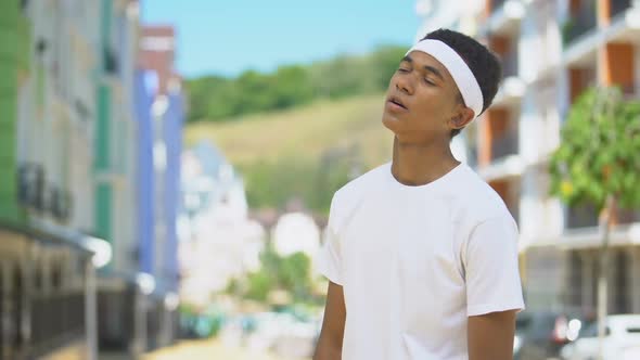 Exhausted Mixed-Race Teen Sportsman Hardly Breathing, Wiping Sweat From Forehead