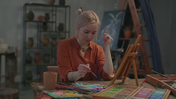 Pensive Female Artist Working on Modern Oil Painting