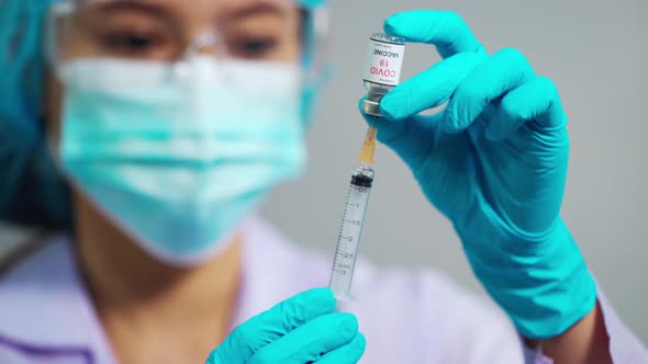 female doctor drawing Coronavirus (Covid-19) vaccine bottle into syringe injection medicine