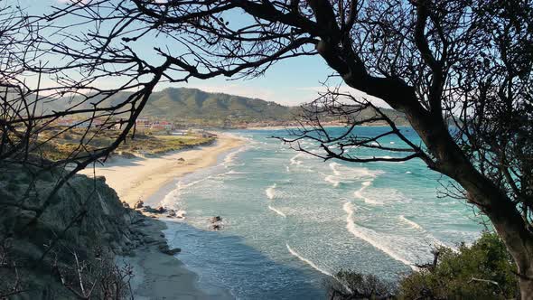 A Picturesque Sea Landscape of a Blue Lagoon with an Empty Public Beach Through Bench of Tree at