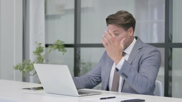 Middle Aged Man Feeling Disappointed While using Laptop in Office