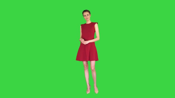 Model Woman in Red Dress Presenting Something Showing with a Hand on Some Object on a Green Screen