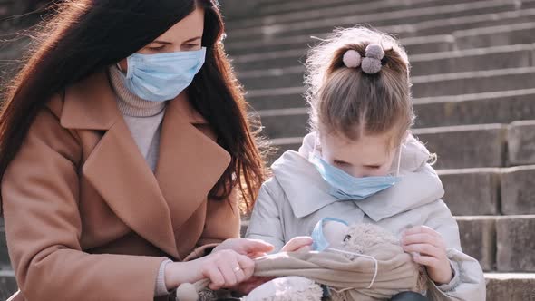 The Mother and Daughter in Masks Are Showing a Teddy Bear Toy in a Mask.