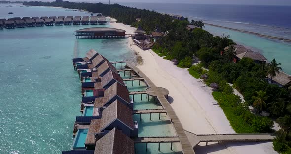 Beautiful fly over tourism shot of a sandy white paradise beach and blue ocean background in colorfu