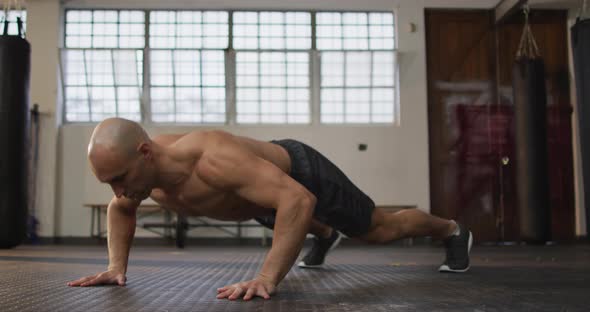 Caucasian muscular shirtless bald man exercising, doing push ups