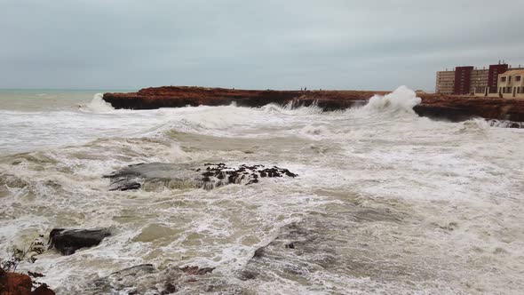 Big Wave Hitting Into Rock Splashing High with Lots of White Foam at Beach in a Windy and Rainy Day