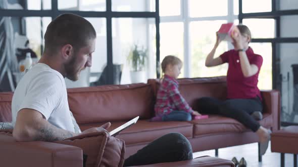 Young Caucasian Man Joining Family Having Fun on Couch and Showing Them Tablet Screen. Happy