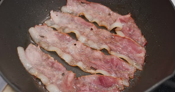 Fry bacon on pan in kitchen for breakfast