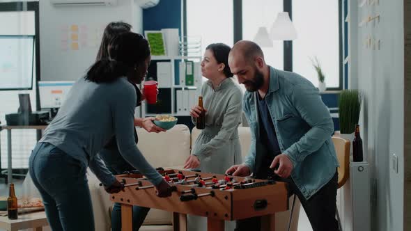 Diverse Group of Workmates Enjoying Game with Foosball Table