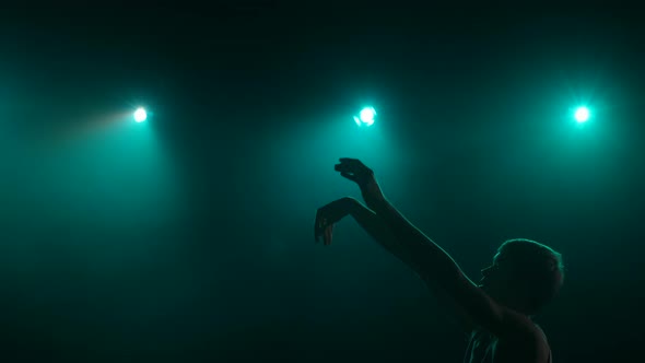 Silhouette of a Young Guy Basketball Player Practicing Throws on a Dark Studio Background with Smoke