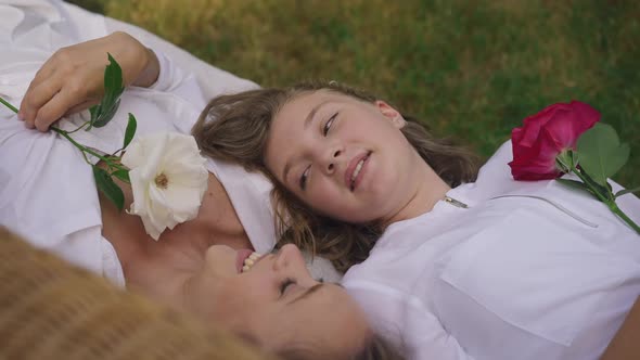 High Angle View Caucasian Teenage Girl and Young Woman with Beautiful Roses Lying on Couch Outdoors