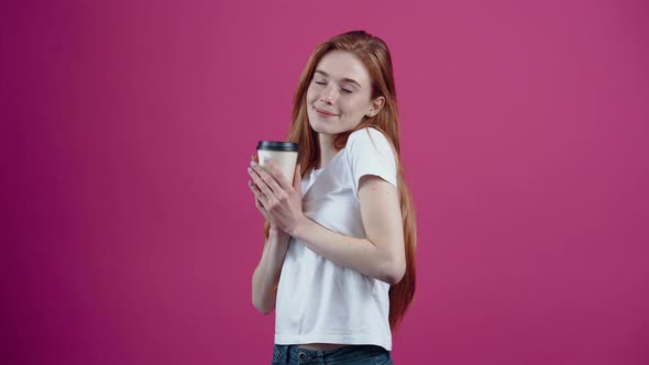 The Redhaired Happy Student Satisfactorily Drinks Coffee From the Paper Cup