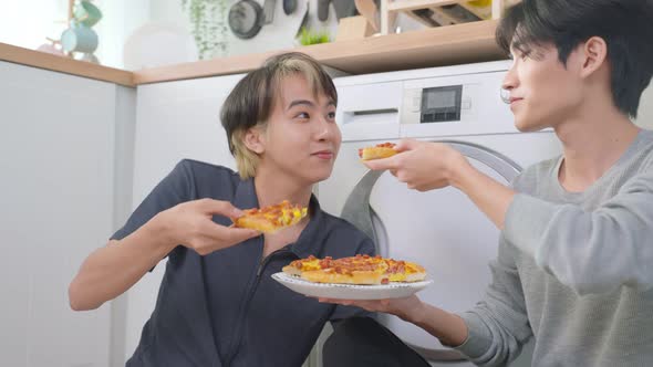 Asian young handsome man gay couple sit on floor and eating pizza together. Homosexual-LGBTQ concept