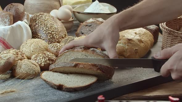 Hands Cutting the Baked Dutch Bread on the Table