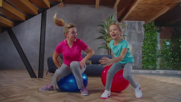 Happy Mom and Child Frolicking on Fitness Balls