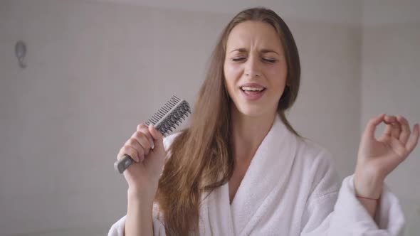 Joyful Confident Young Woman Having Fun Singing in Hairbrush in the Morning at Home