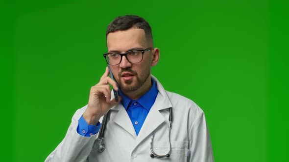 Portrait of Serious Professional Male Doctor with Stethoscope Stands Isolated on Green Background